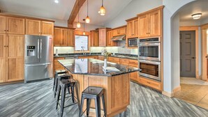 A modern kitchen with wooden cabinets, stainless steel appliances, a granite countertop, and pendant lighting. - Dock, Hot Tub & Game Room: Luxe Lake Latoka Home (Alexandria)
