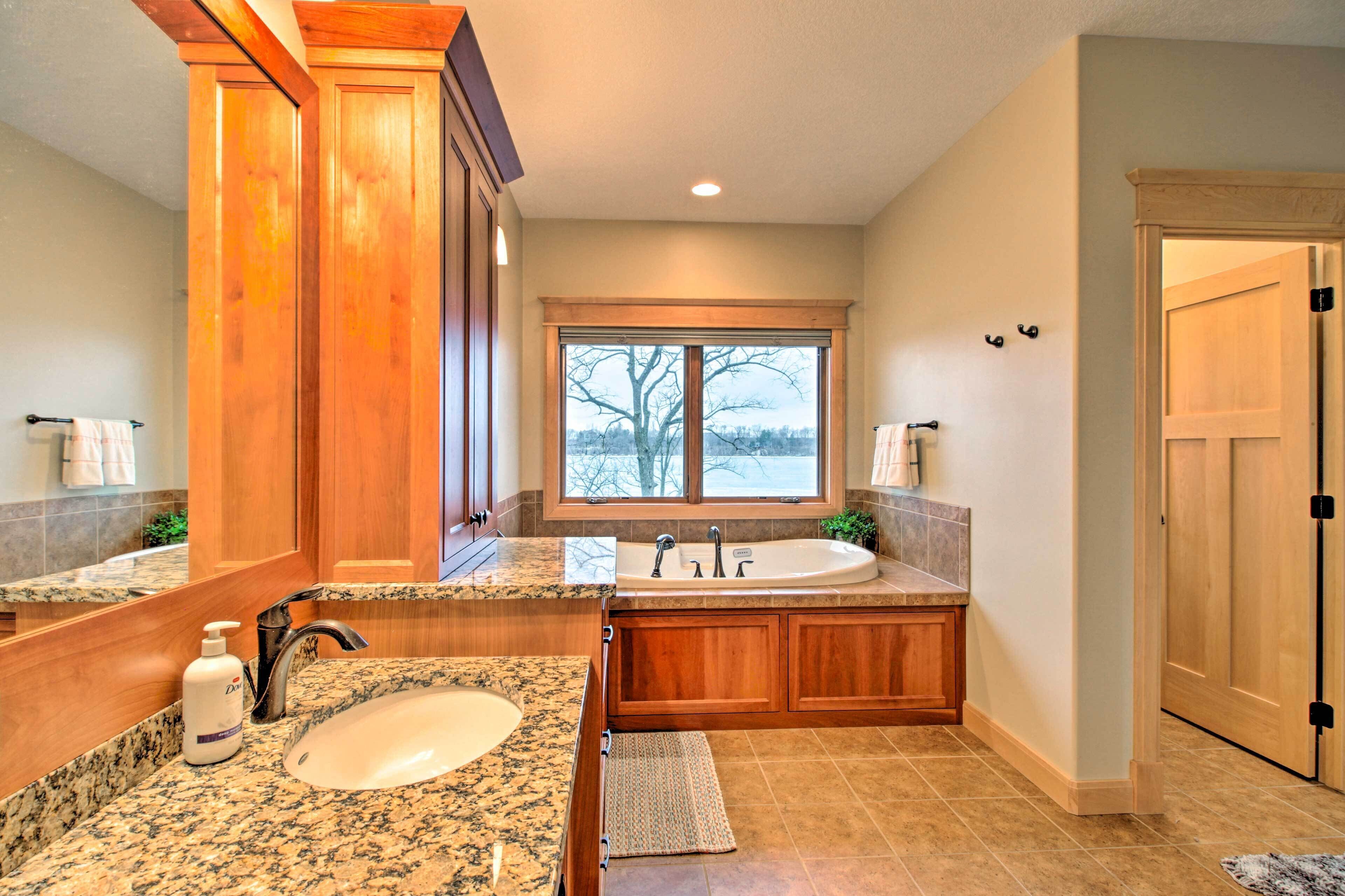 A bathroom with a large sink, vanity, and bathtub.