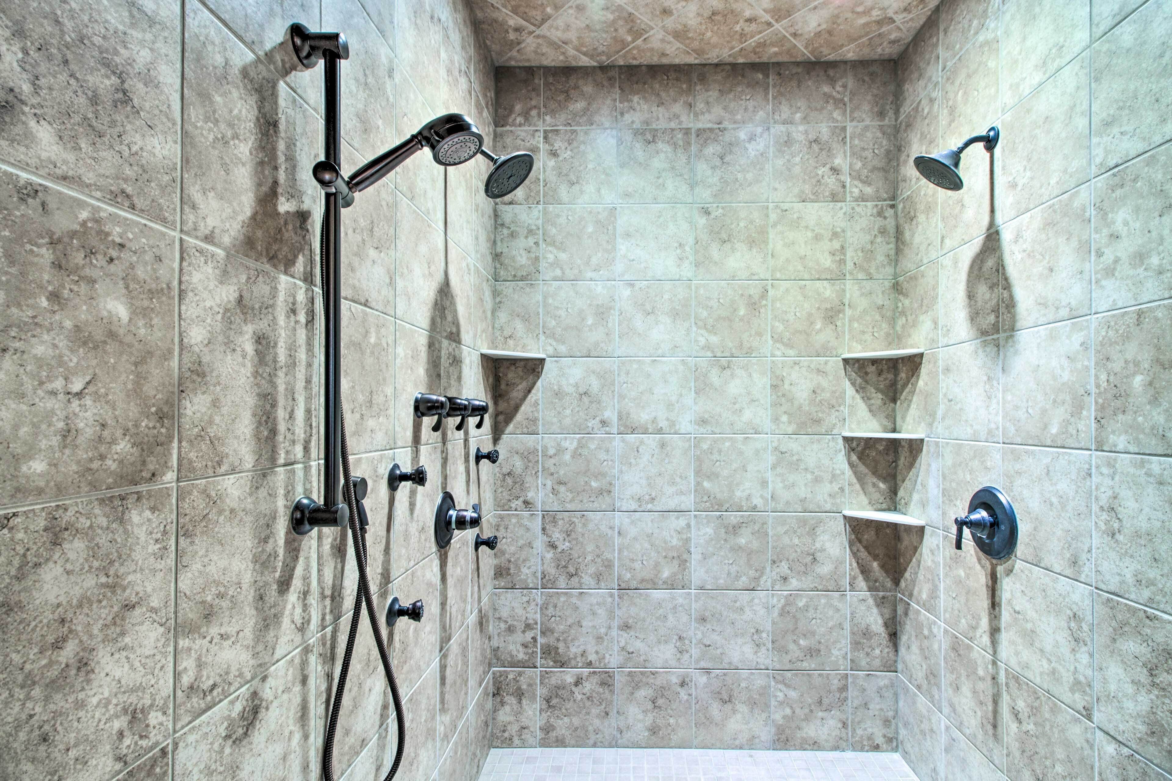 A shower area with multiple showerheads and a handheld shower attachment.