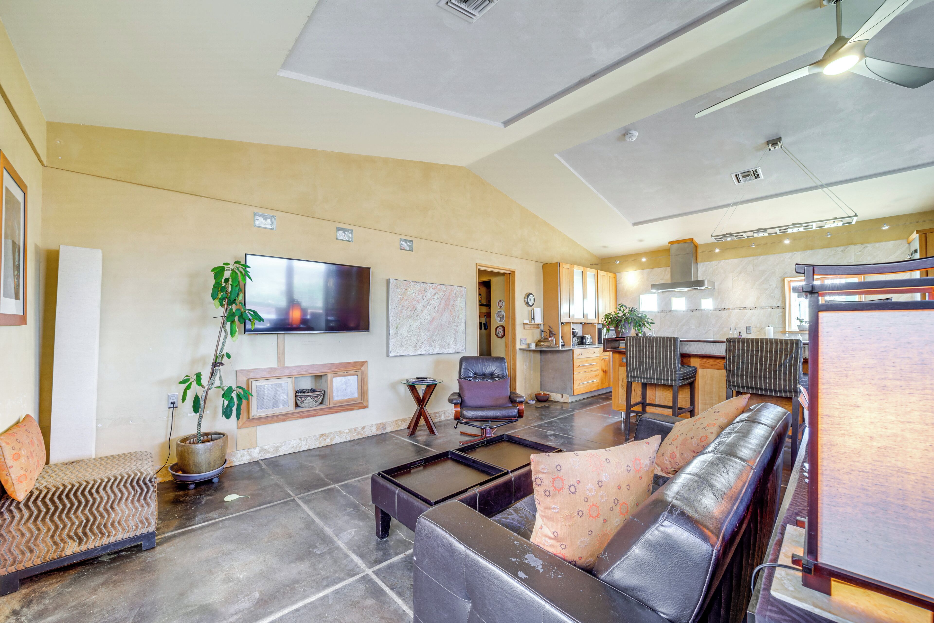 A spacious living area with a sofa, a coffee table, a TV, and a kitchen in the background.
