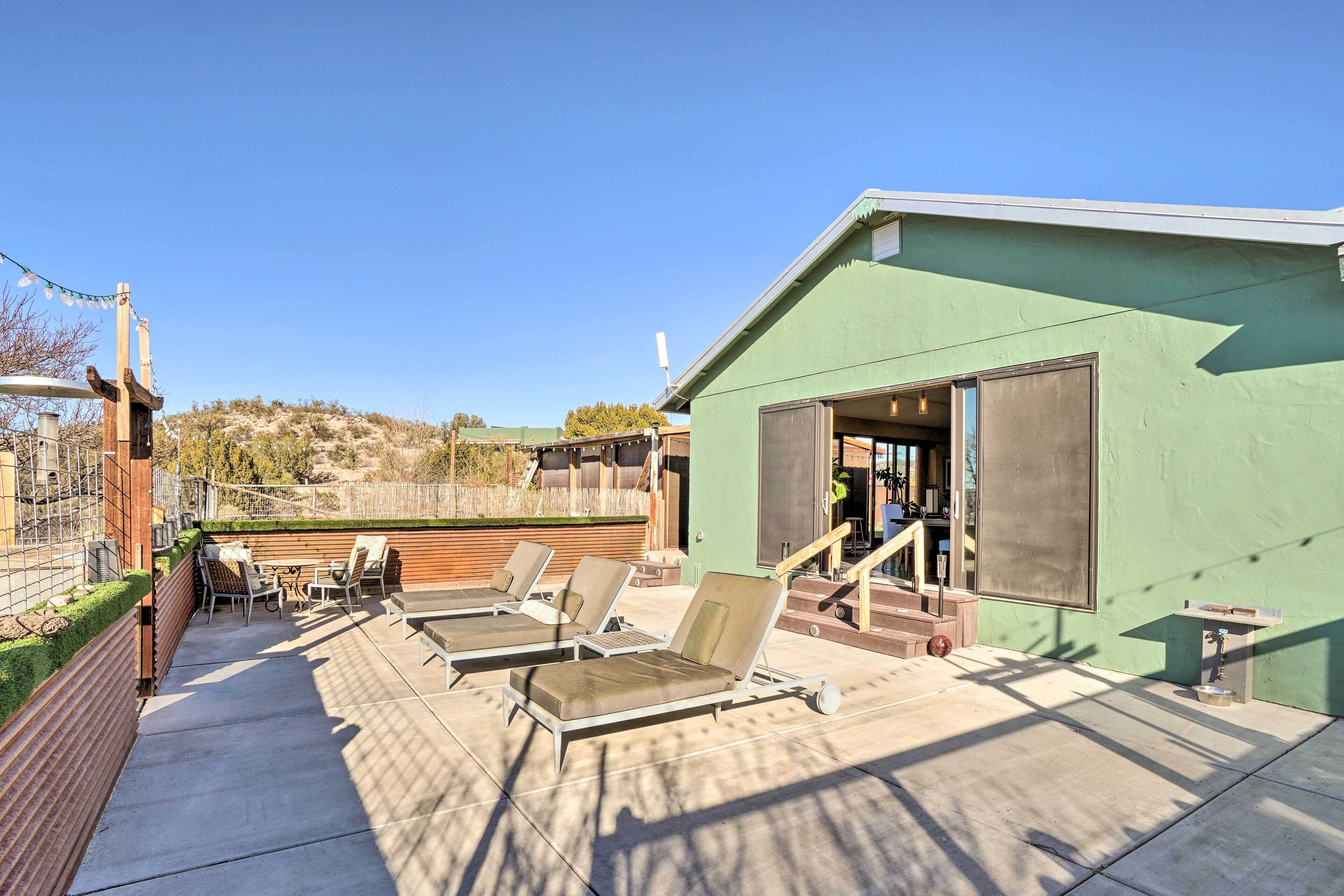 A rooftop patio with lounge chairs and a small building with a green exterior.