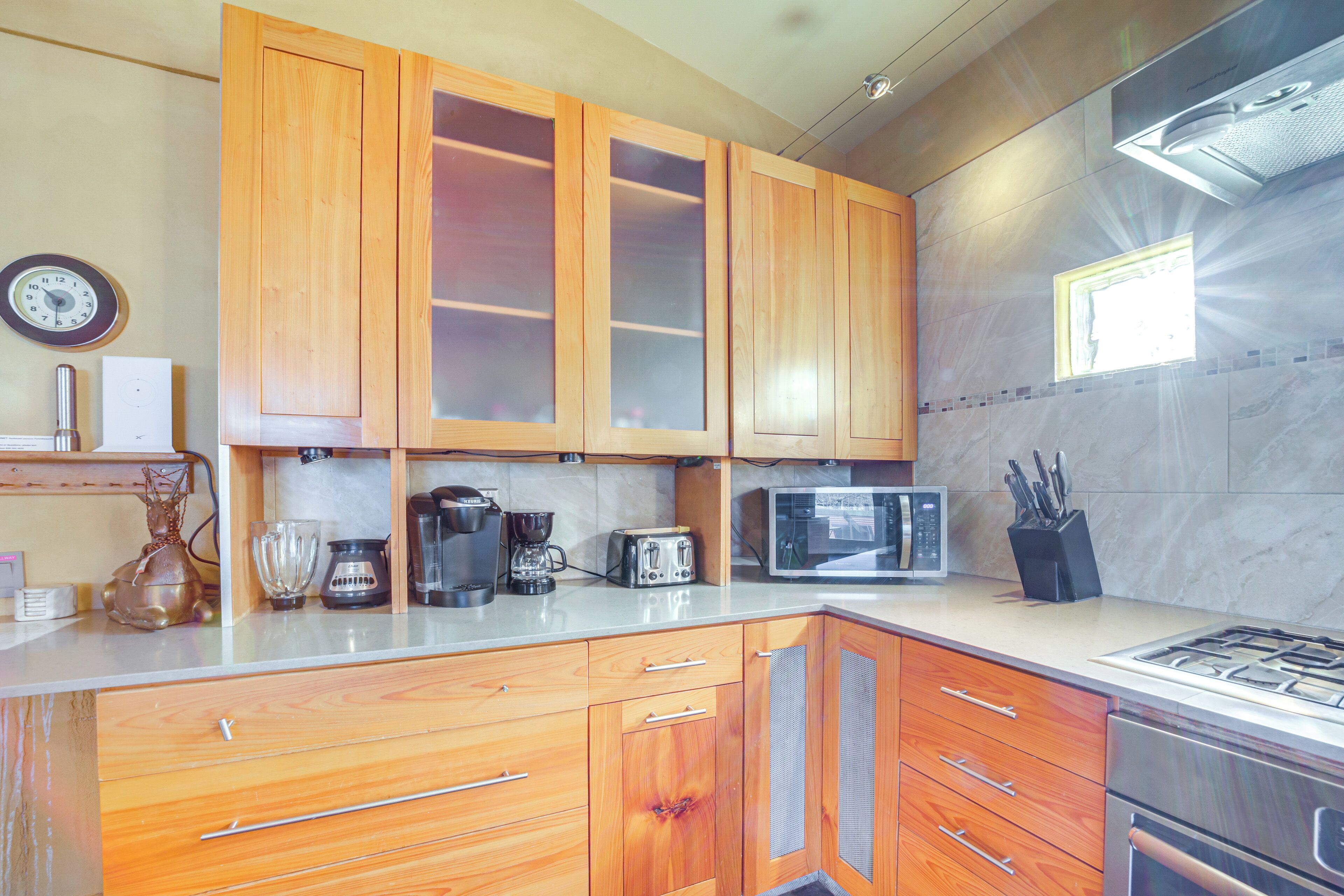 A kitchen with wooden cabinets, a microwave, a coffee maker, and a gas stove.