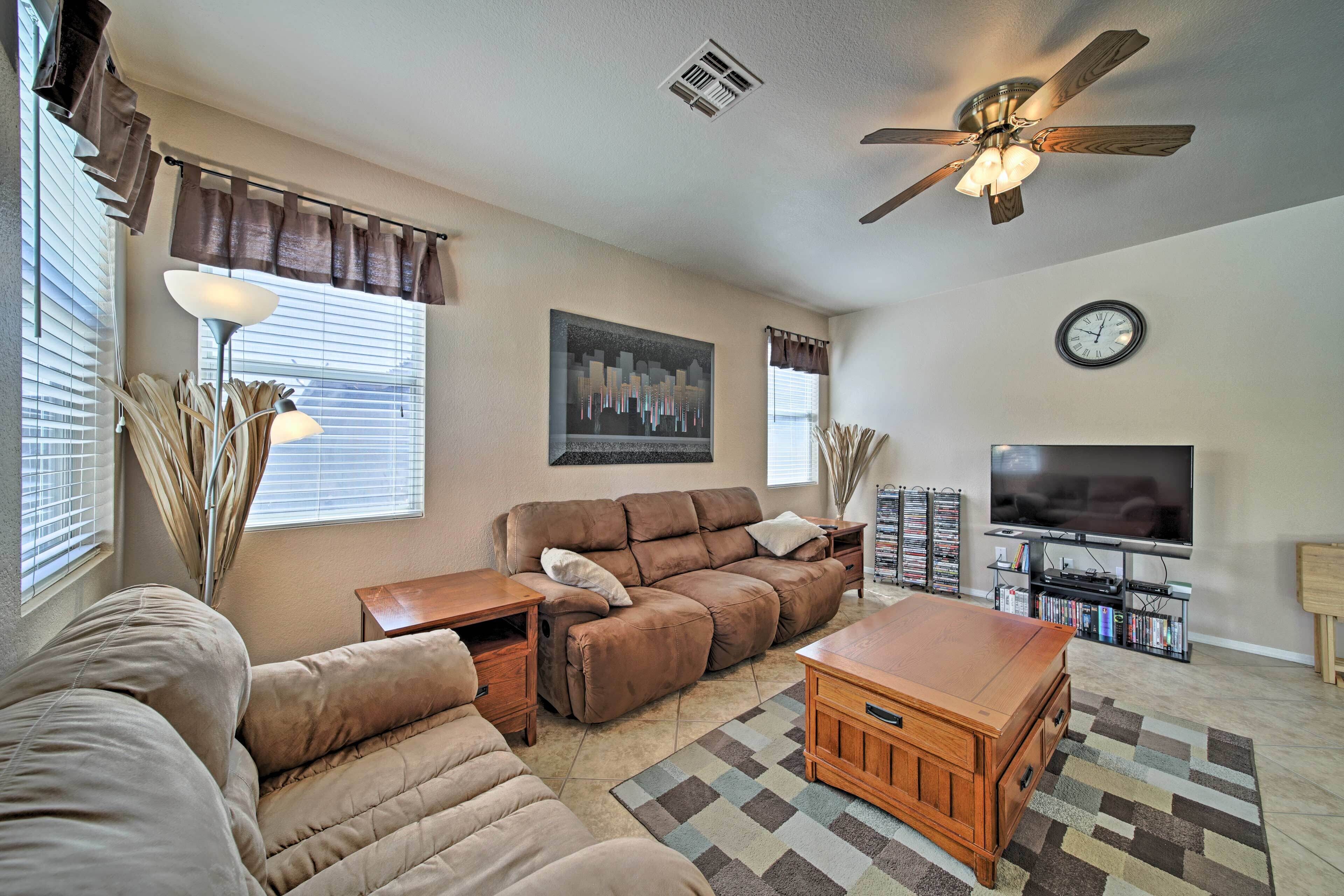 A living room with a sectional sofa, a recliner, a coffee table, a TV, and a ceiling fan.