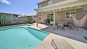 A backyard with a swimming pool, patio furniture, and a hammock. - 2 Mi to Goodyear Ballpark! Home w/ Poolside Oasis (Goodyear)