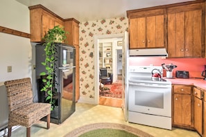 A compact kitchen with wooden cabinets, a refrigerator, an oven, and a microwave. - Restored 1930s Cottage on 1 Acre w/ Fire Pit (Hayes)