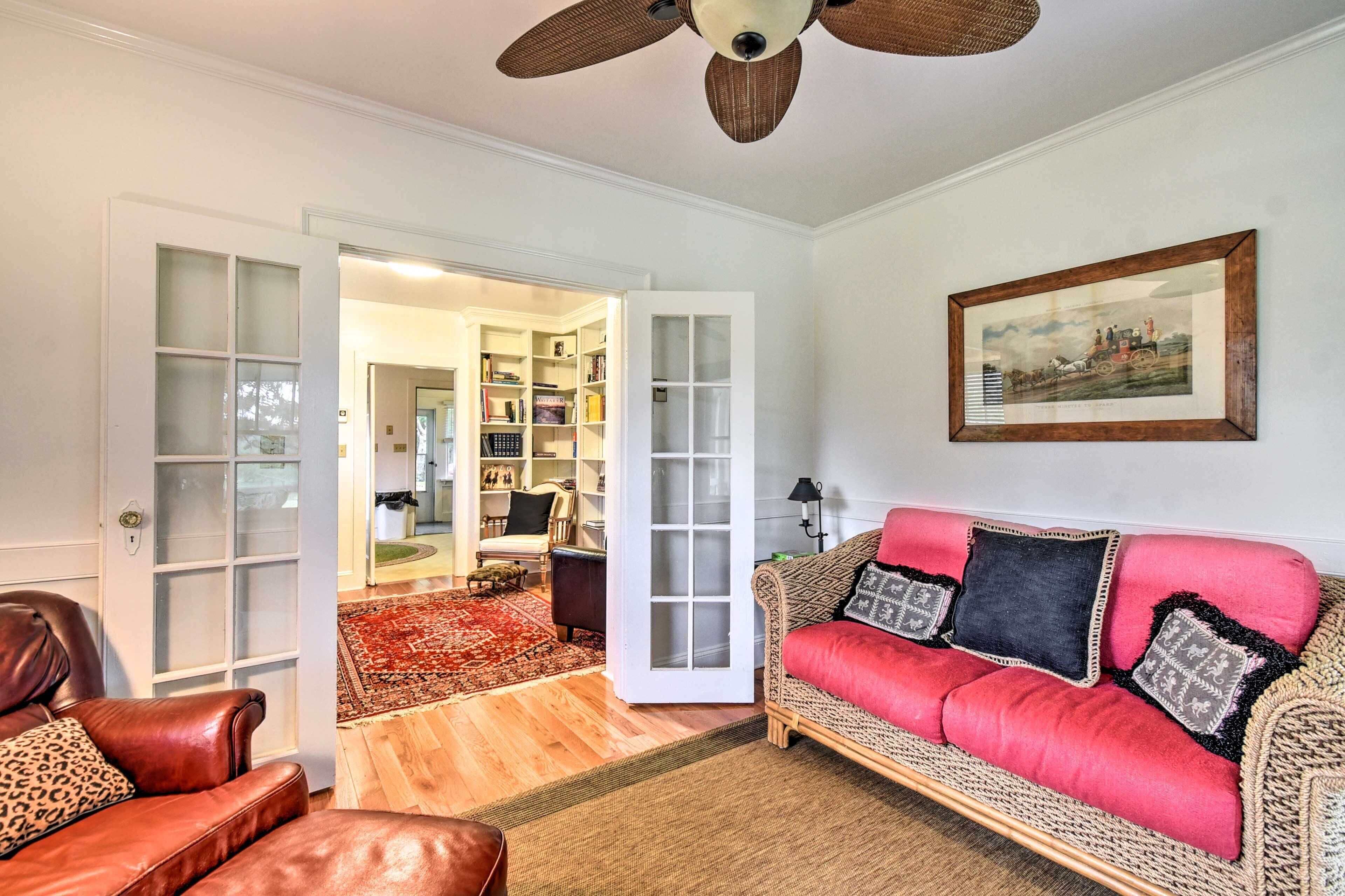 A living room with a red sofa, a brown leather chair, and a ceiling fan.