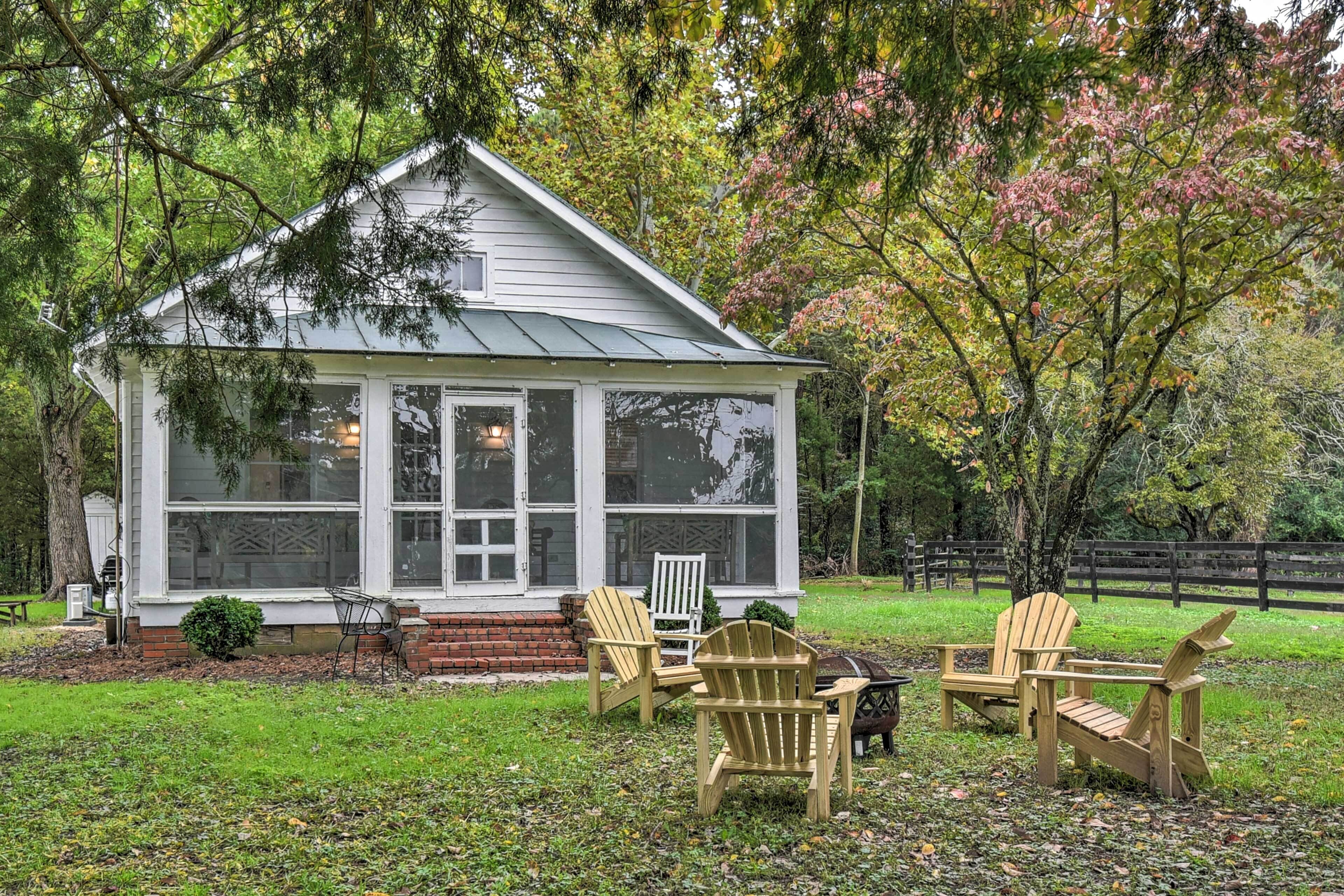 Una casetta con un portico, tre poltrone in stile Adirondack e un vialetto in mattoni che conduce all'ingresso.