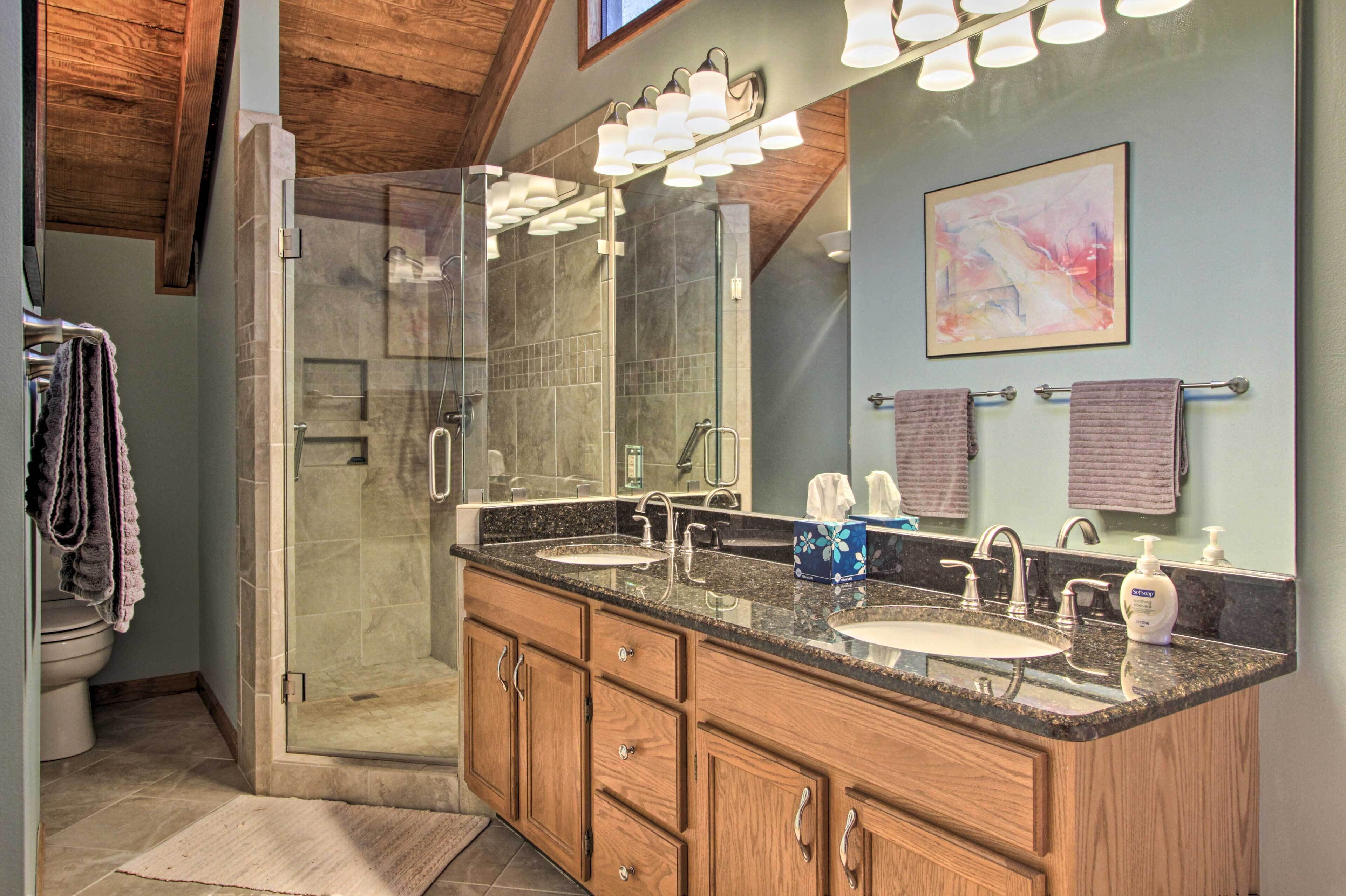 A modern bathroom with a walk-in shower, double sinks, and a large mirror.