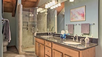 A modern bathroom with a walk-in shower, double sinks, and a large mirror.