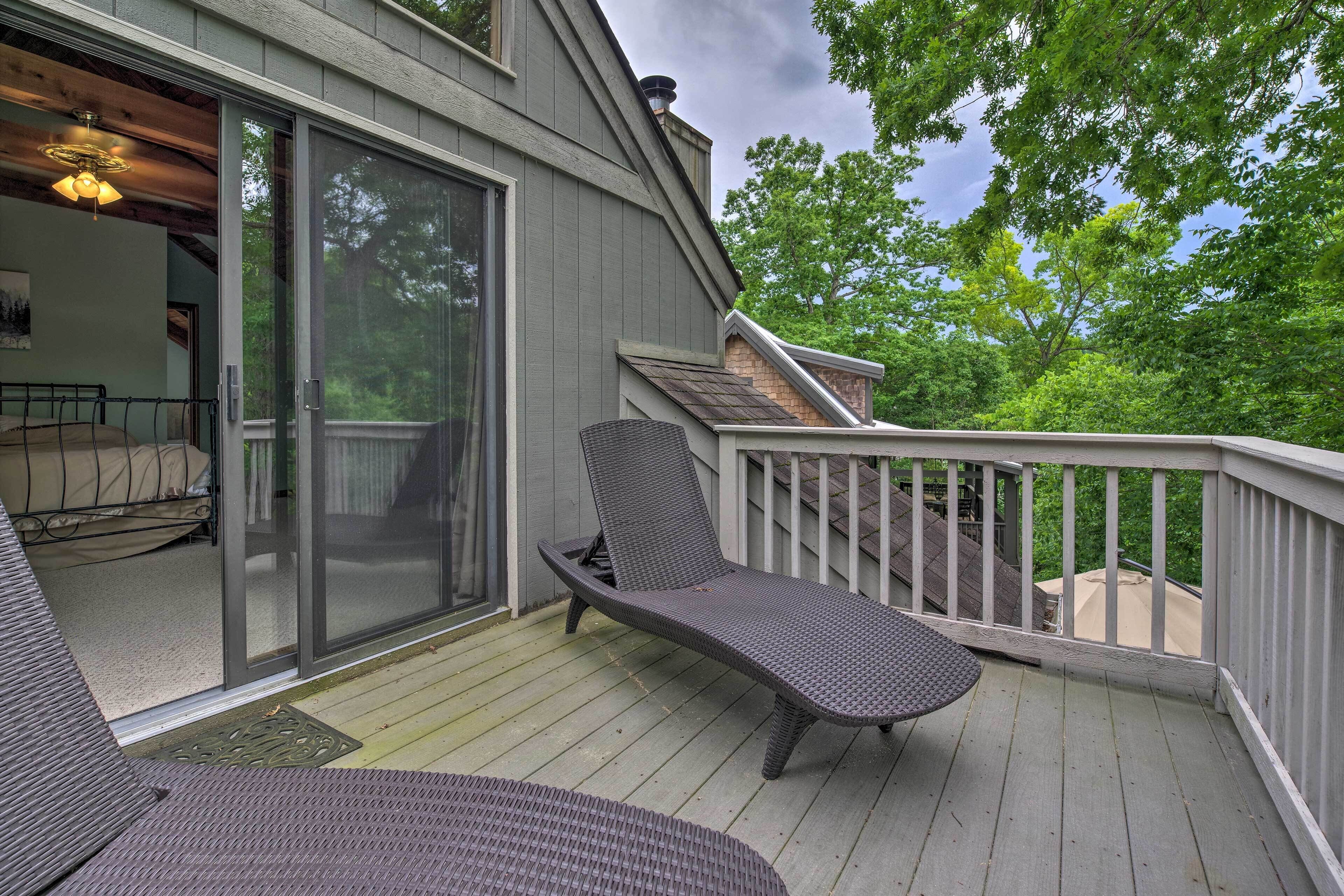 A deck with a sliding glass door leading to a bedroom, a lounge chair, and a small table.