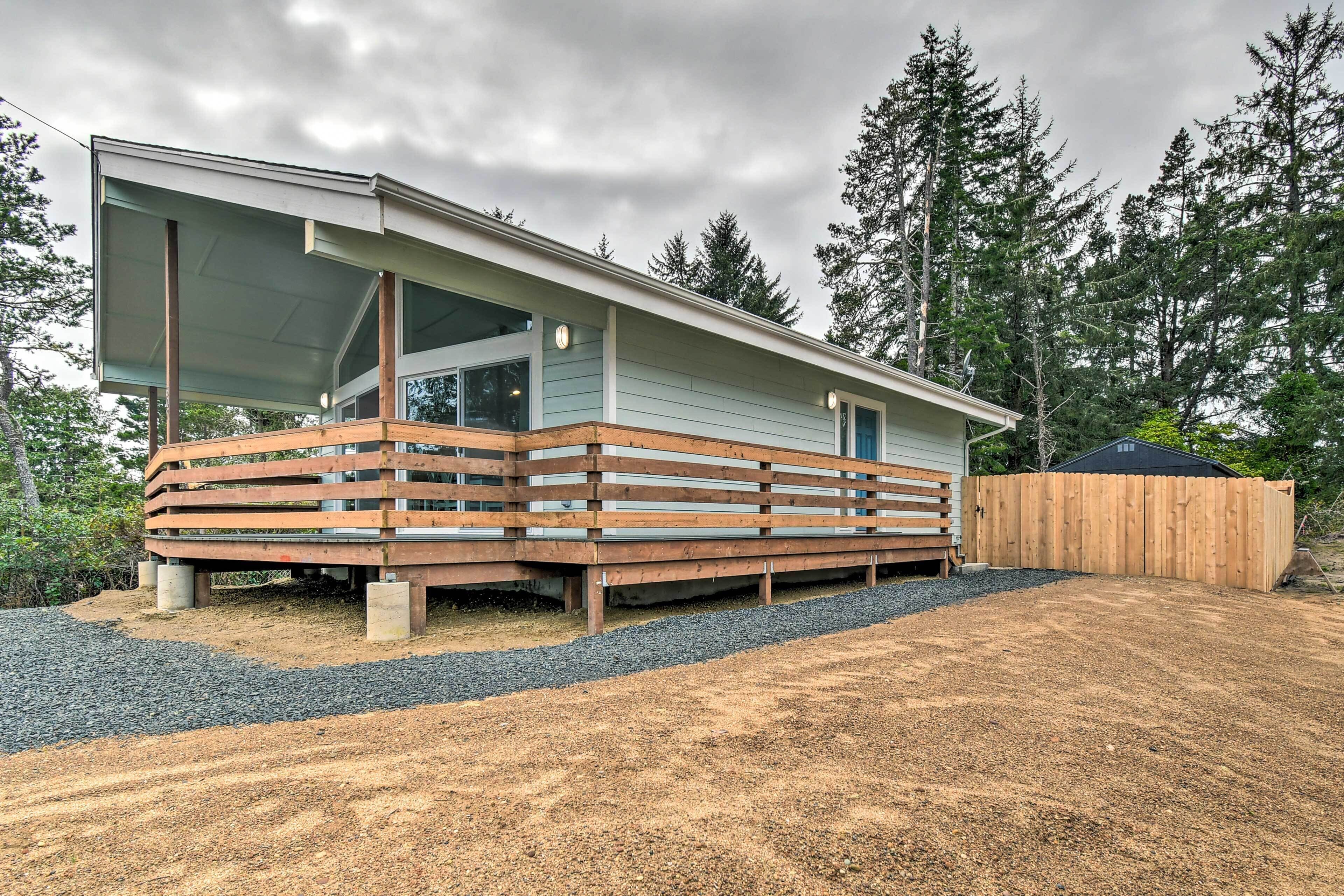 A modern house with a large deck, a covered porch, and a wooden fence.