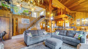 A spacious living room with a large gray sectional sofa, a wooden staircase, and a chandelier. - Waterfront Truckee Cabin on Donner Lake! (Truckee)