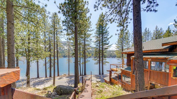 A wooden deck leading to a cabin with a view of a lake surrounded by trees. - Waterfront Truckee Cabin on Donner Lake! (Truckee)