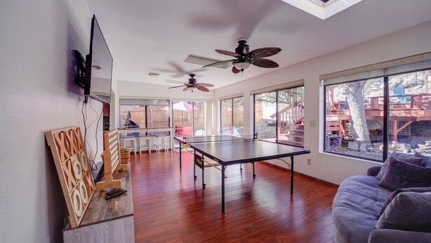 A spacious living area with a ping pong table, ceiling fans, and large windows offering views of the outdoors. - 2 Mi to Whiskey Row: Tranquil Getaway w/ Deck! (Prescott)