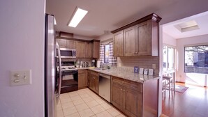 A modern kitchen with wooden cabinets, stainless steel appliances, and a large window providing natural light. - 2 Mi to Whiskey Row: Tranquil Getaway w/ Deck! (Prescott)