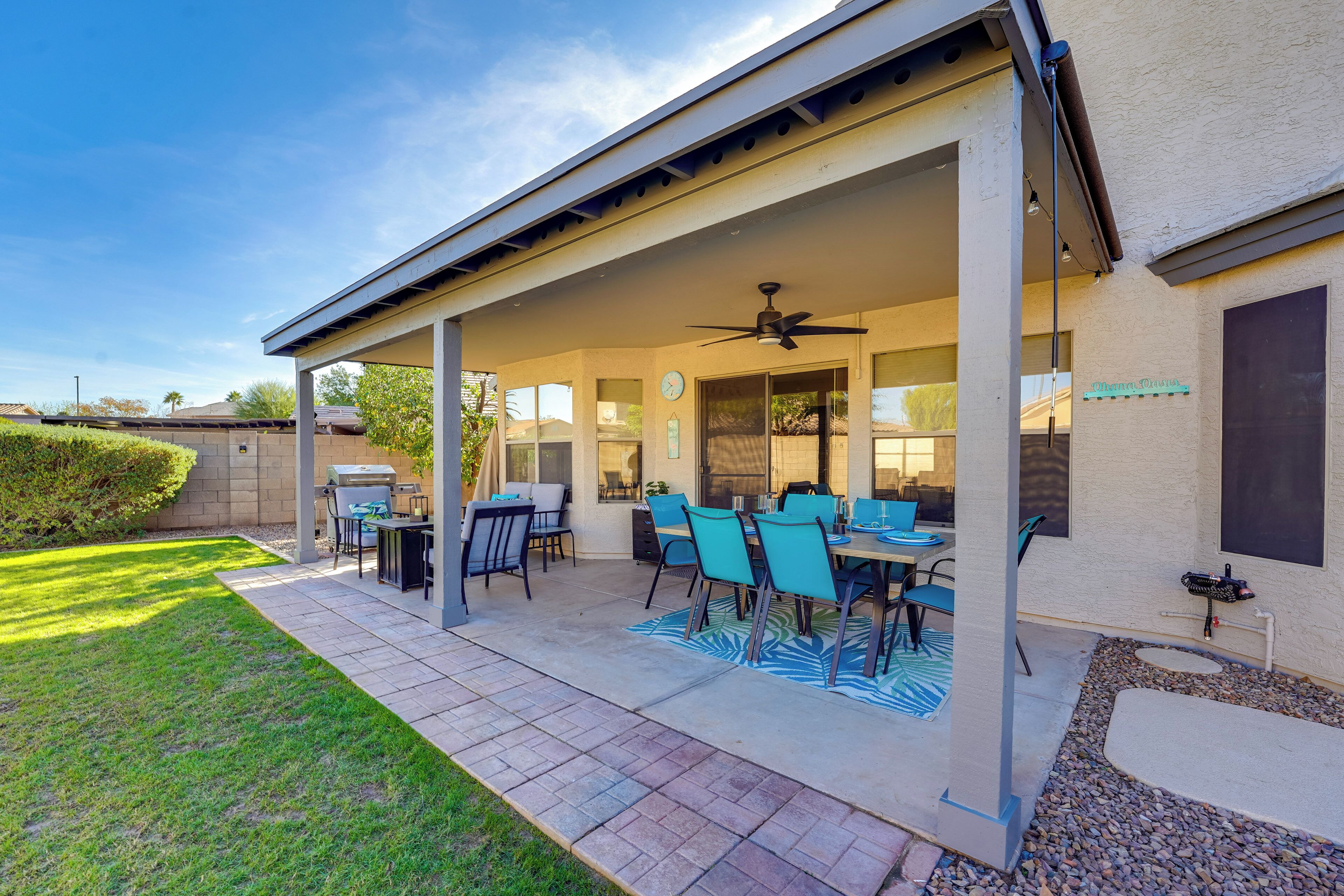 A covered patio with a dining table and chairs, a ceiling fan, and a view of the backyard.