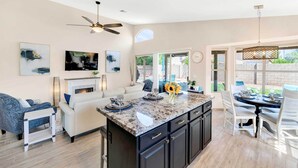 A modern kitchen with a central island, dark cabinetry, and a dining area with a round table and chairs. - Close to Spring Training! Serene Retreat in Gibert (Gilbert)