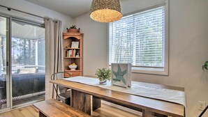 A modern dining area with a wooden table, bench, and a hanging light fixture.
