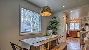 A dining area with a wooden table, chairs, and a hanging light fixture.