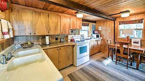 A wooden kitchen with a large sink, stove, and dining area. - Serene Washington Escape w/ Deck & Mountain Views! (Packwood)