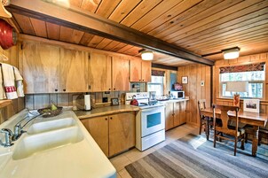 Cocina de madera con un fregadero grande, estufa y comedor.