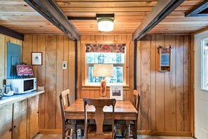 A wooden-paneled room with a dining table and chairs, a microwave, and a sign that reads "Catered Here." - Serene Washington Escape w/ Deck & Mountain Views! (Packwood)