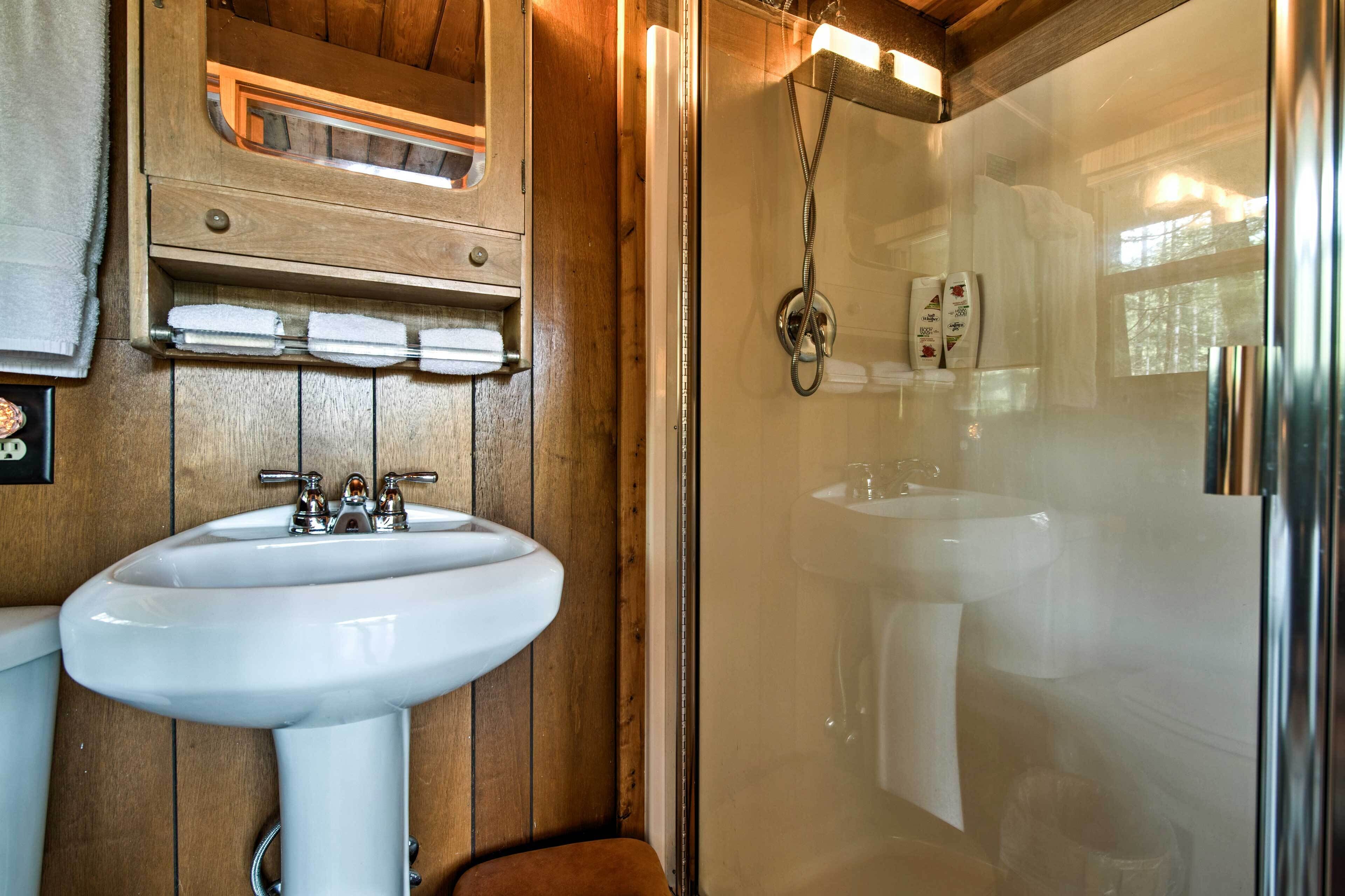 A bathroom with a wooden interior, a glass-enclosed shower, and a white sink.