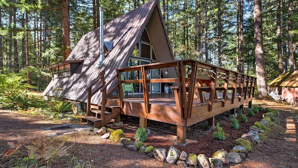A cabin with a sloped roof, wooden deck, and a small porch. - Serene Washington Escape w/ Deck & Mountain Views! (Packwood)