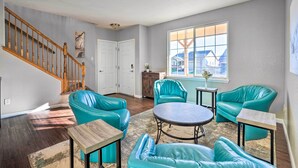 A living room with teal leather sofas, a wooden coffee table, and a staircase. - Spacious Springs Home + Patio ~ 10 Mi to Dtwn (Colorado Springs)
