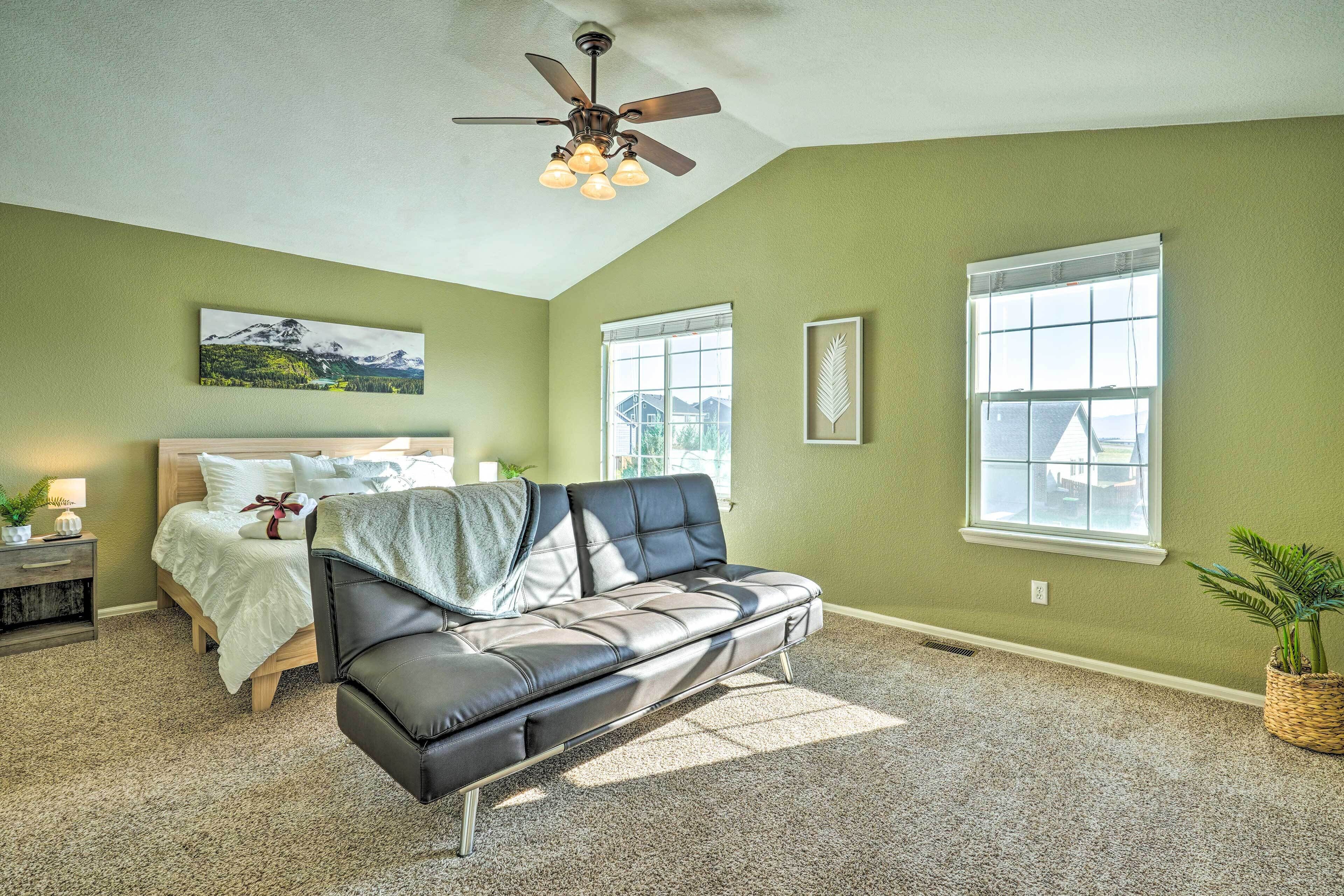 Ein Schlafzimmer mit Bett, Sofa, Deckenventilator und Fenster.