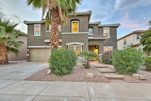 A two-story house with a garage, surrounded by a landscaped garden with palm trees and shrubs. - Spacious Gilbert Escape w/ Pool & Hot Tub! (Gilbert)