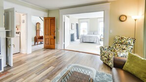 A spacious living room with hardwood flooring, a sofa, a patterned armchair, and a view into another room. - Kennebunk Apartment w/ Local Beach Access! (Kennebunk)