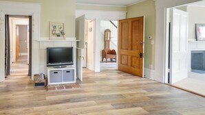 A spacious living room with a fireplace, a television, and a wooden door. - Kennebunk Apartment w/ Local Beach Access! (Kennebunk)