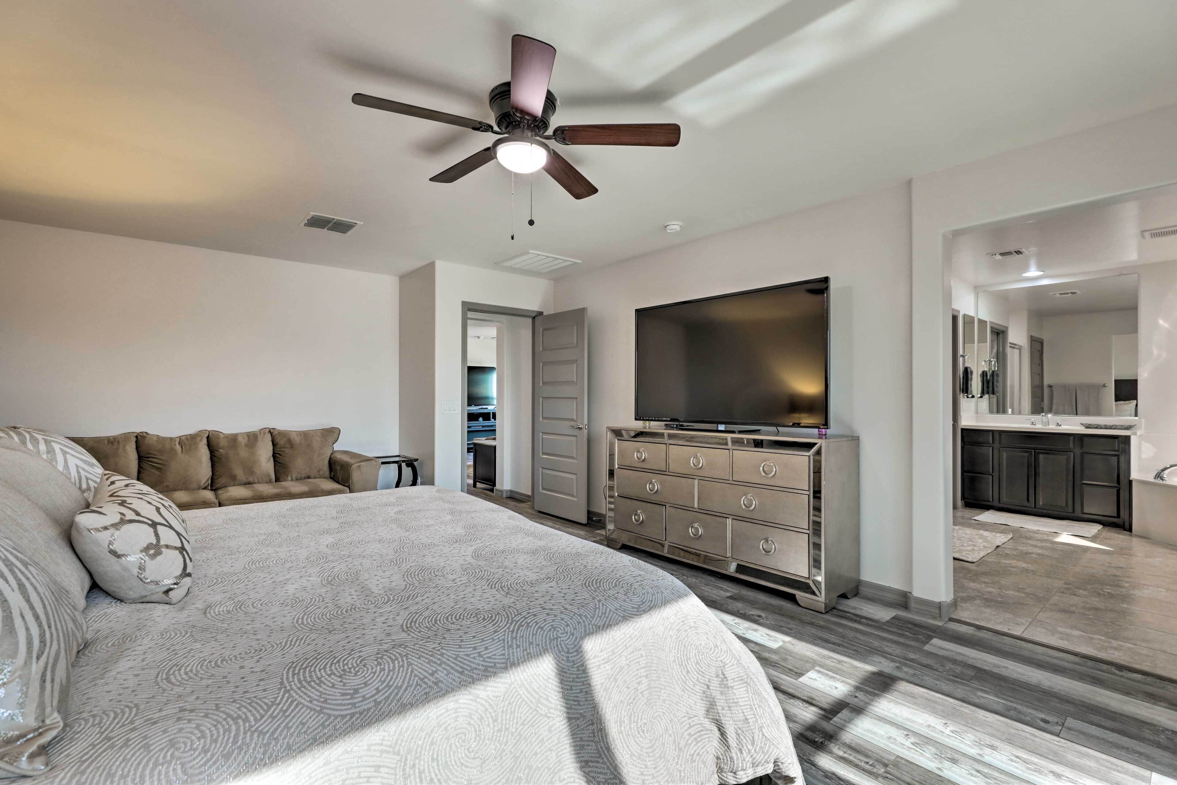 A bedroom with a bed, a dresser, a TV, and a ceiling fan.