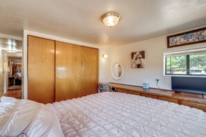 Un dormitorio con una cama grande, un armario de madera, un espejo y un cuadro en la pared.