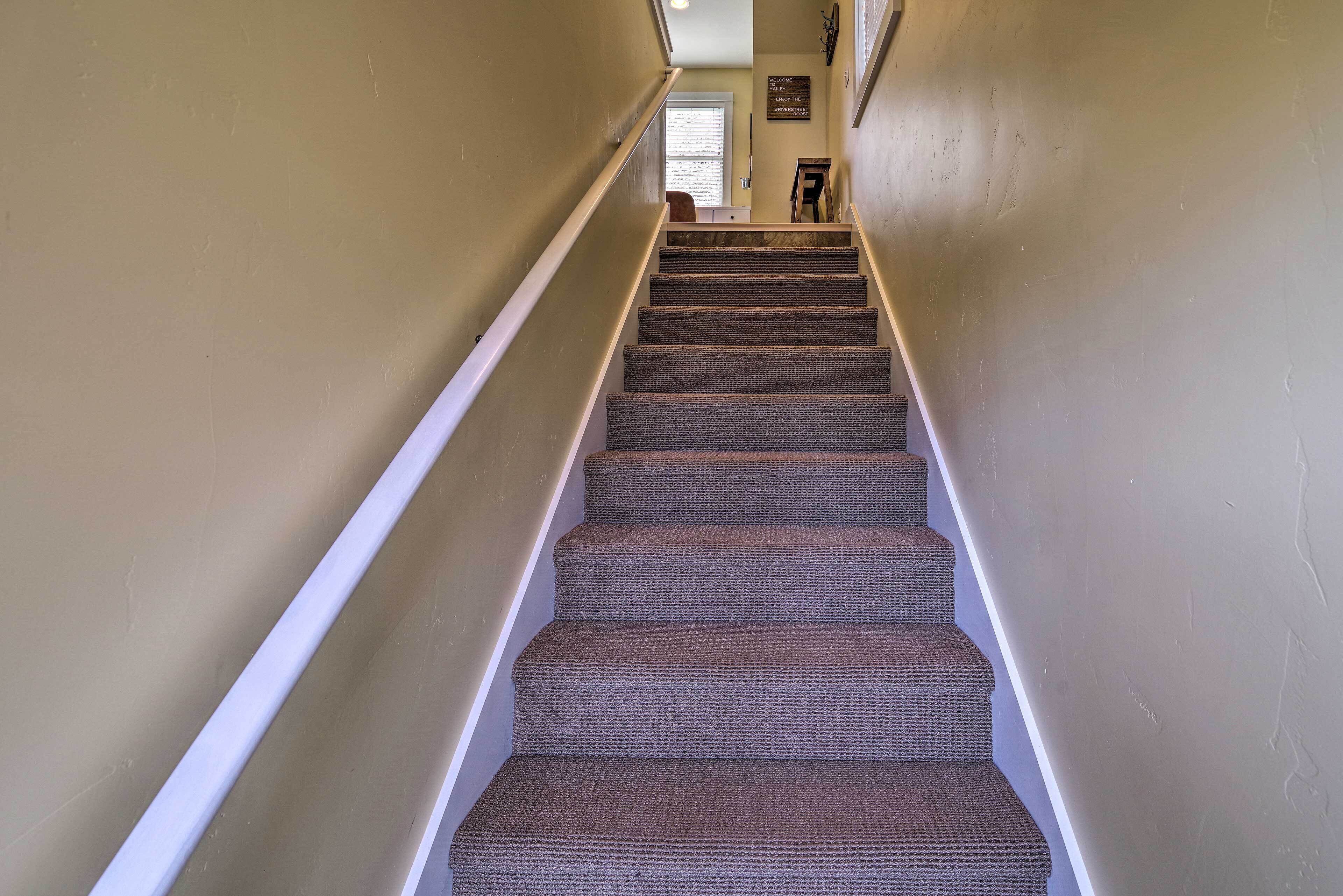 A carpeted staircase with white handrails, leading to a door at the top.