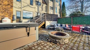 A patio area with a stone fire pit, outdoor seating, and a propane tank.