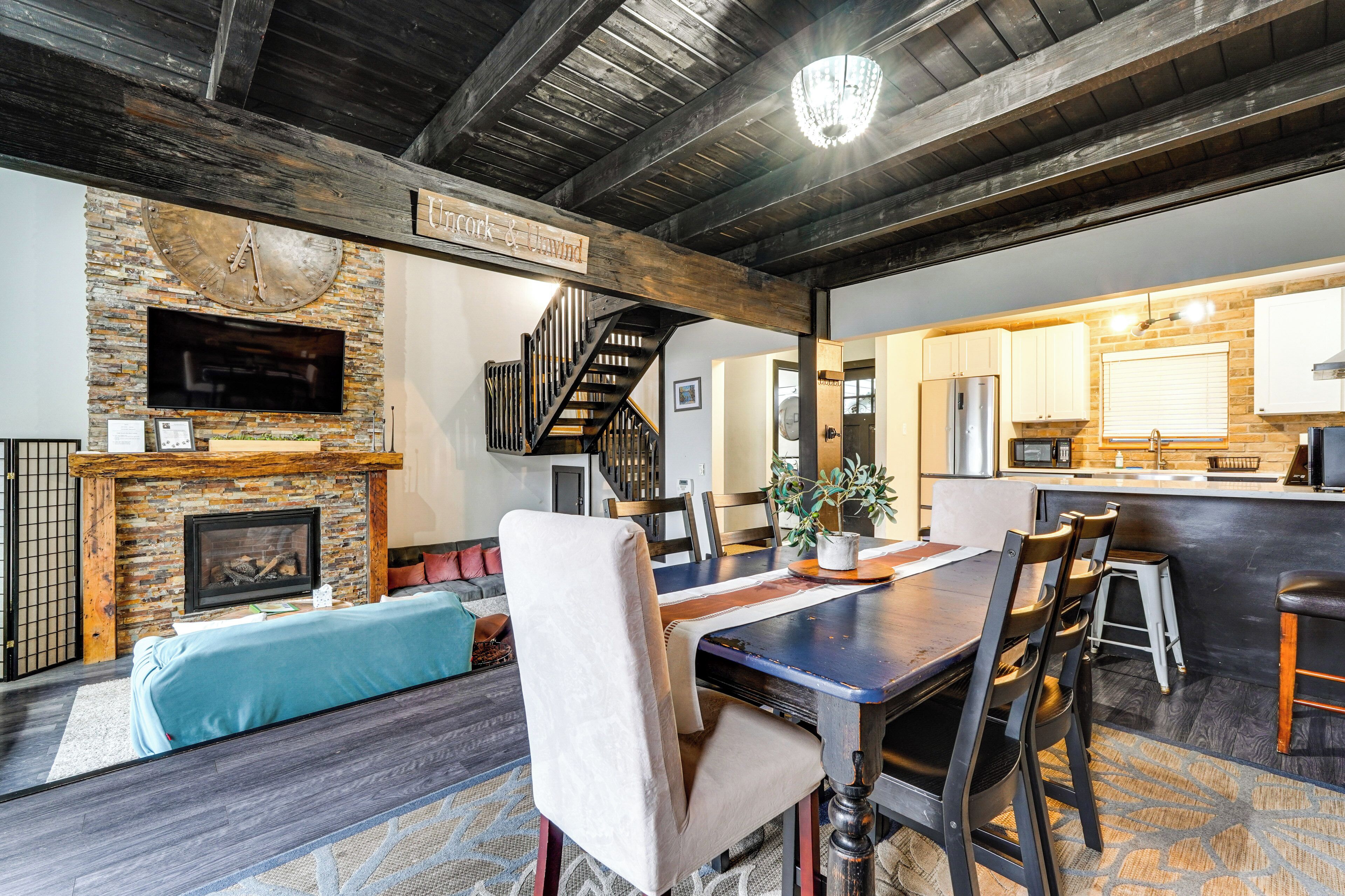 A spacious living area with a fireplace, a dining table, and a kitchen in the background.