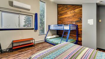 A room with a bunk bed, a bench, a window with curtains, and a wooden wall.