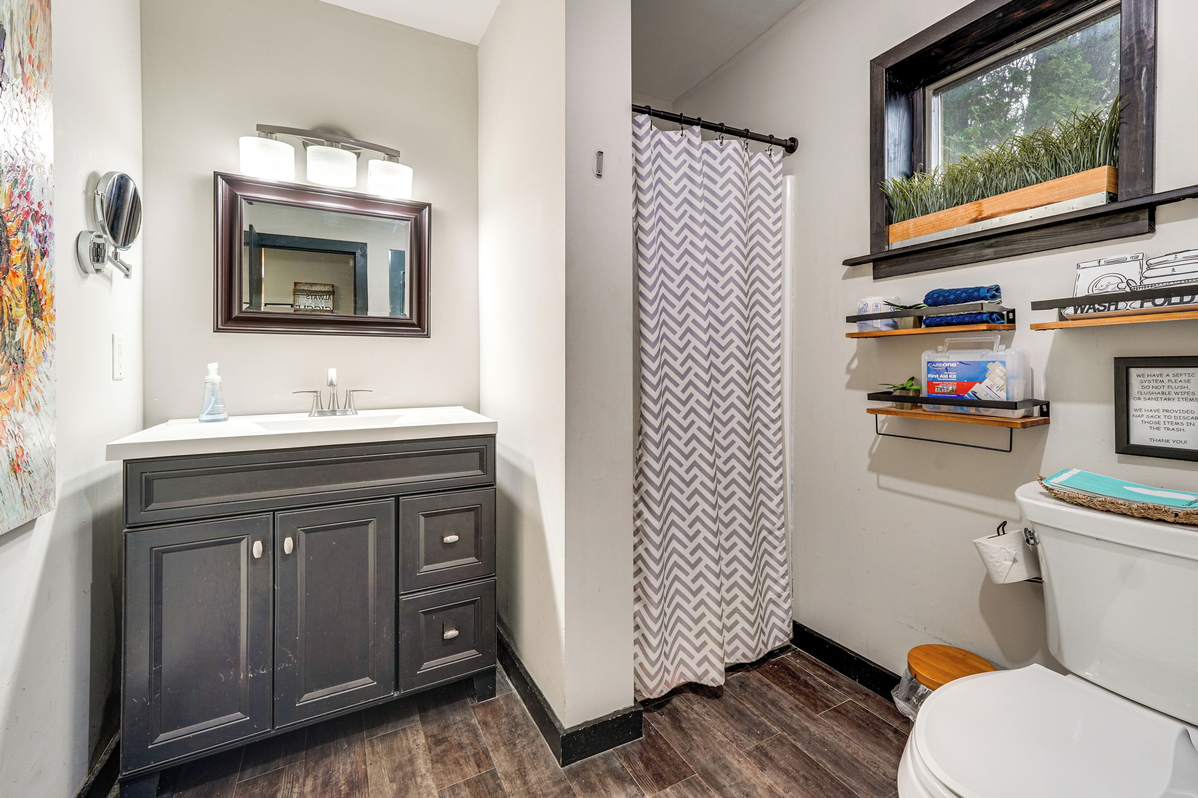 Une salle de bain avec un meuble-lavabo en bois foncé, un miroir, un rideau de douche et des toilettes.