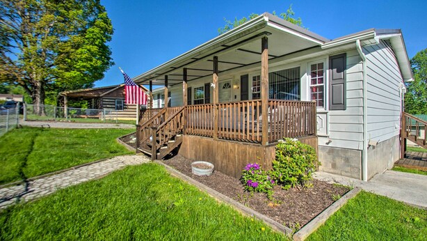 A single-story house with a porch, a small garden, and a flag.