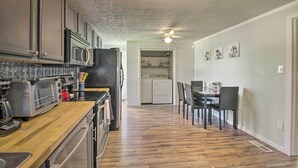 A kitchen with a wooden countertop, stainless steel appliances, and a dining area with a table and chairs.