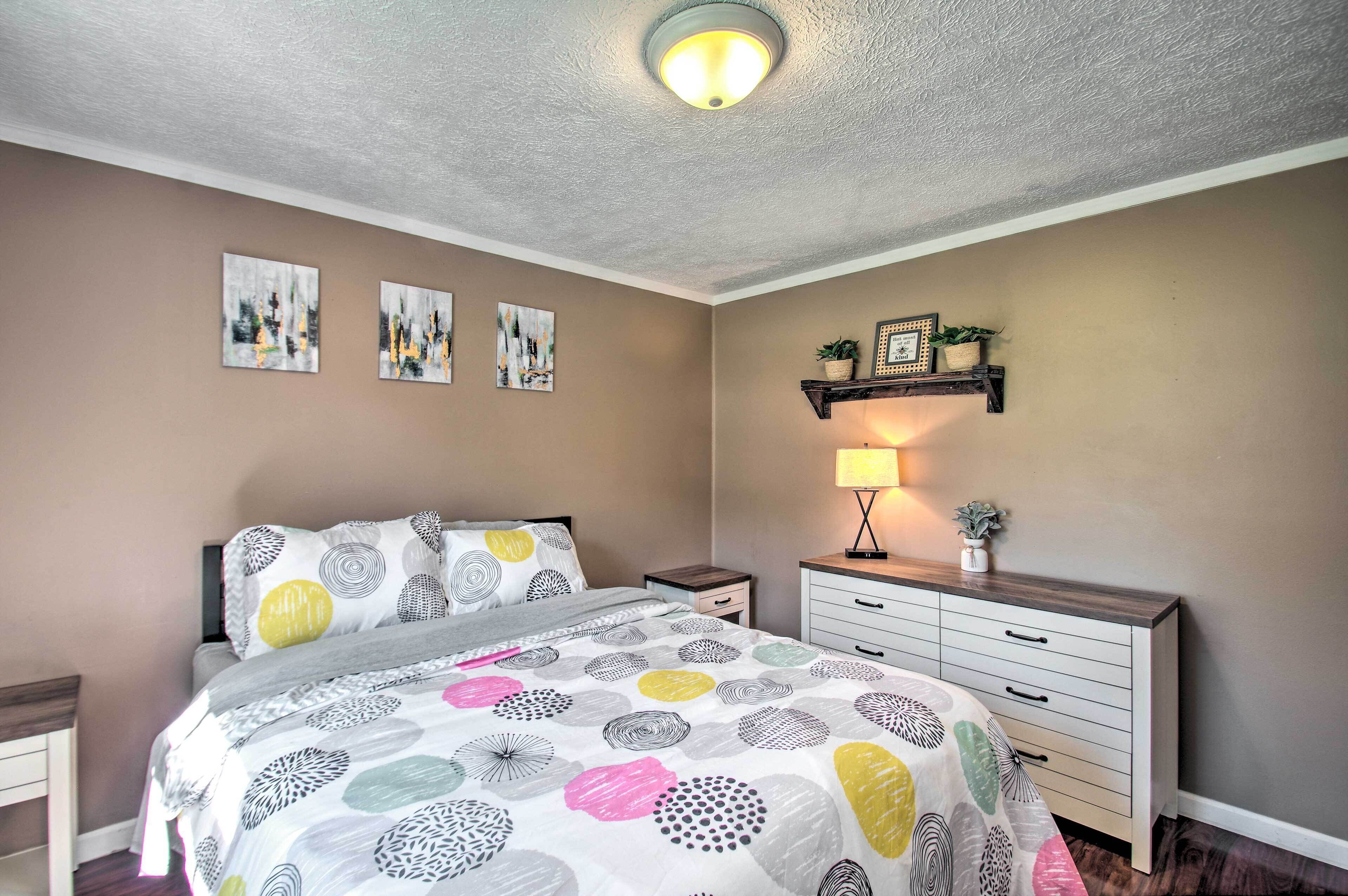 A bedroom with a bed, bedside tables, a dresser, and wall art.