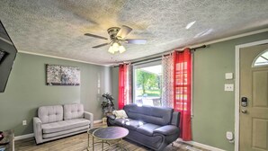 A living room with a ceiling fan, two sofas, a small round table, and a door with a keypad lock.