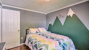 A bedroom with a bed, a door, and a wall with a mountain design.