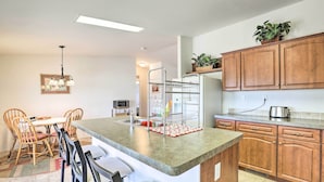 A kitchen with wooden cabinets, a granite countertop, a built-in oven, and a dining area with chairs and a table. - Quiet Tombstone Retreat ~ 3 Mi to Historic Dtwn! (Tombstone)
