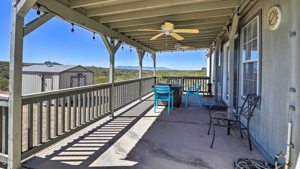 A covered porch with a ceiling fan, two blue chairs, and a table. - Quiet Tombstone Retreat ~ 3 Mi to Historic Dtwn! (Tombstone)