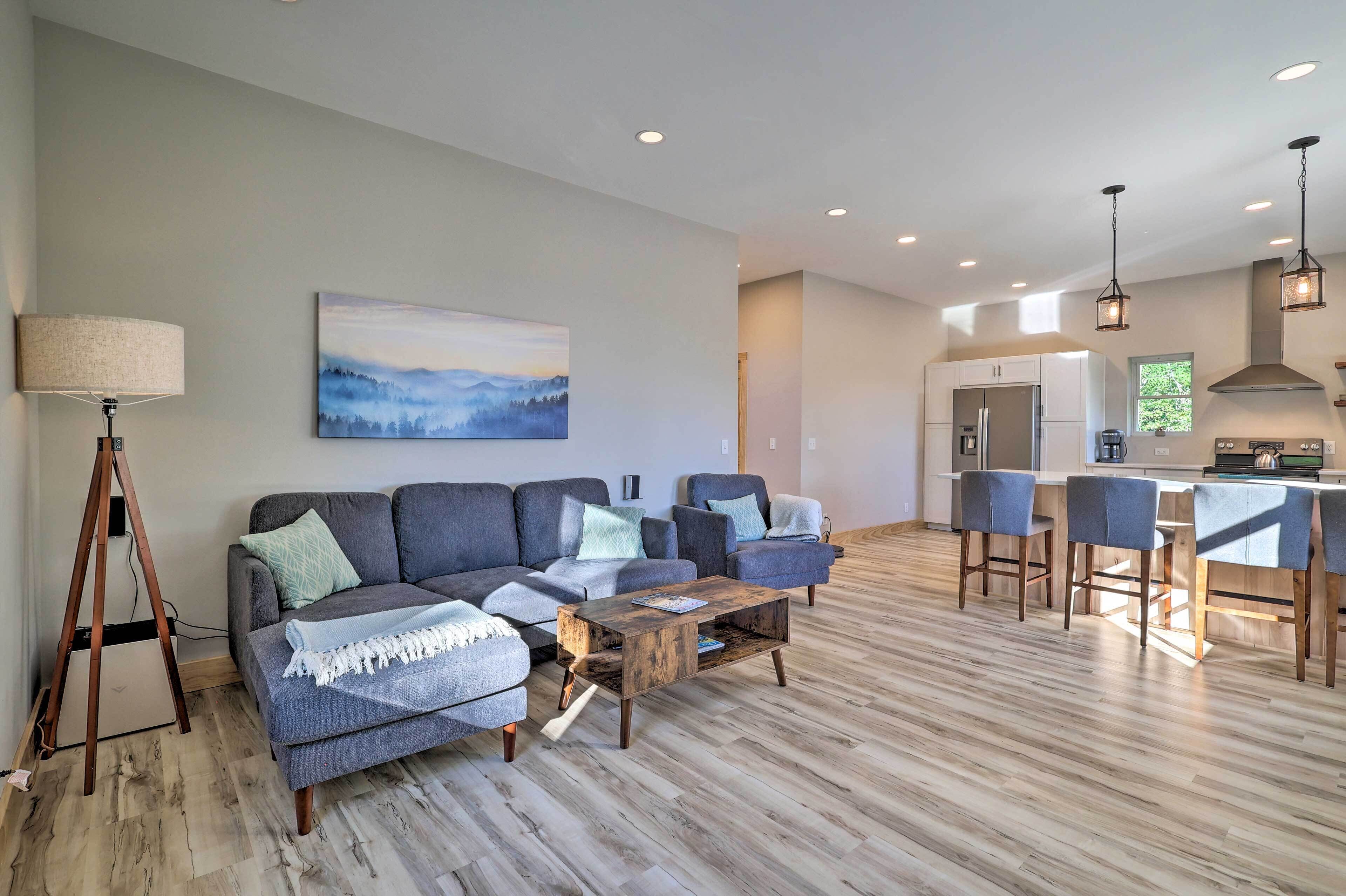 A modern living room with a sofa set, a coffee table, and a dining area with bar stools.