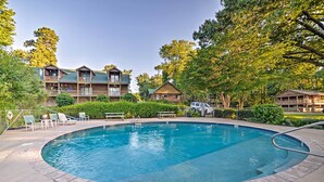 A pool area with a 2 ft diving board, lounge chairs, and a building with multiple balconies. - Group-friendly Cabin on Kentucky Lake! (Springville)