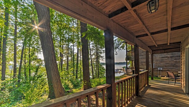 A wooden deck with a railing overlooking a forested area and a body of water. - Group-friendly Cabin on Kentucky Lake! (Springville)